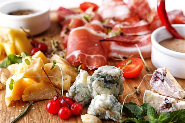 Various cheeses and cold meats with sauces and berries, on a wooden board, on a wooden board